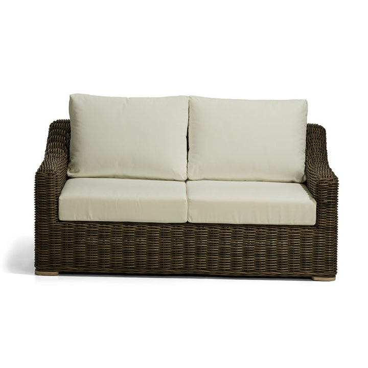 Sofá de dos plazas con estructura de mimbre marrón oscuro y cojines de asiento y respaldo en color crema claro. No hay inscripciones visibles ni detalles escritos en el producto.