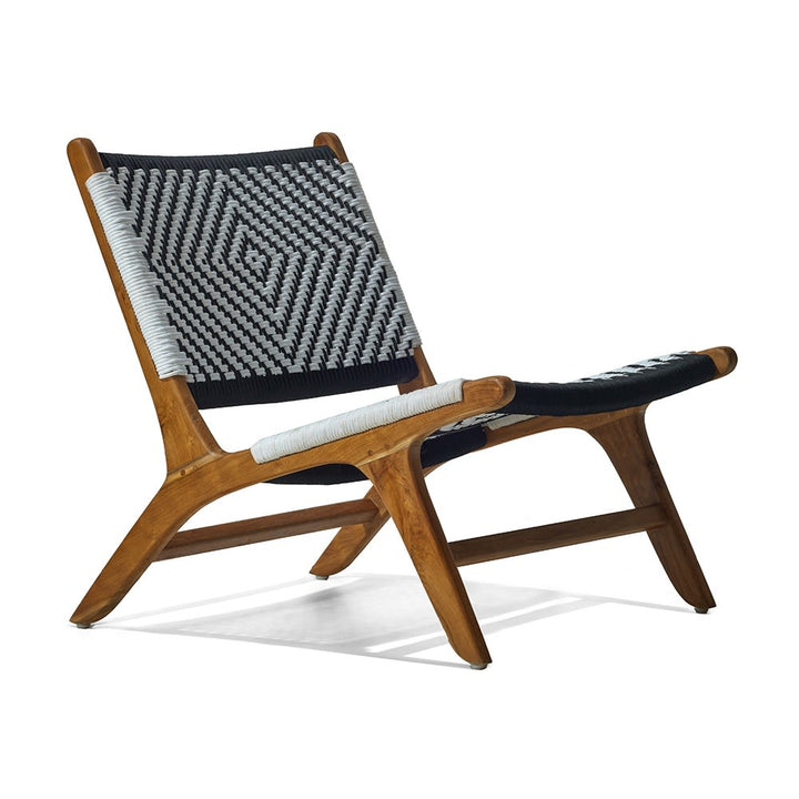 Silla de madera con estructura inclinada y asiento y respaldo tejidos a mano en patrón geométrico en blanco y negro. El diseño combina estilo moderno con artesanía tradicional.