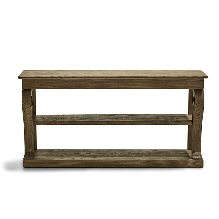 Mesa de madera rectangular con dos estantes inferiores y acabado envejecido, diseñada en un estilo rústico con patas gruesas y detalles curvados.
