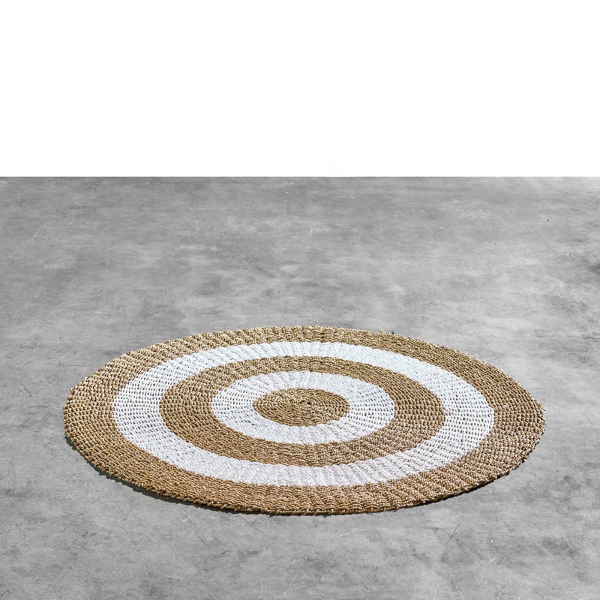 Alfombra redonda de fibra natural tejida a mano con un diseño de anillos concéntricos alternando entre marrón claro natural y blanco. El patrón simétrico proporciona un estilo decorativo moderno y orgánico.