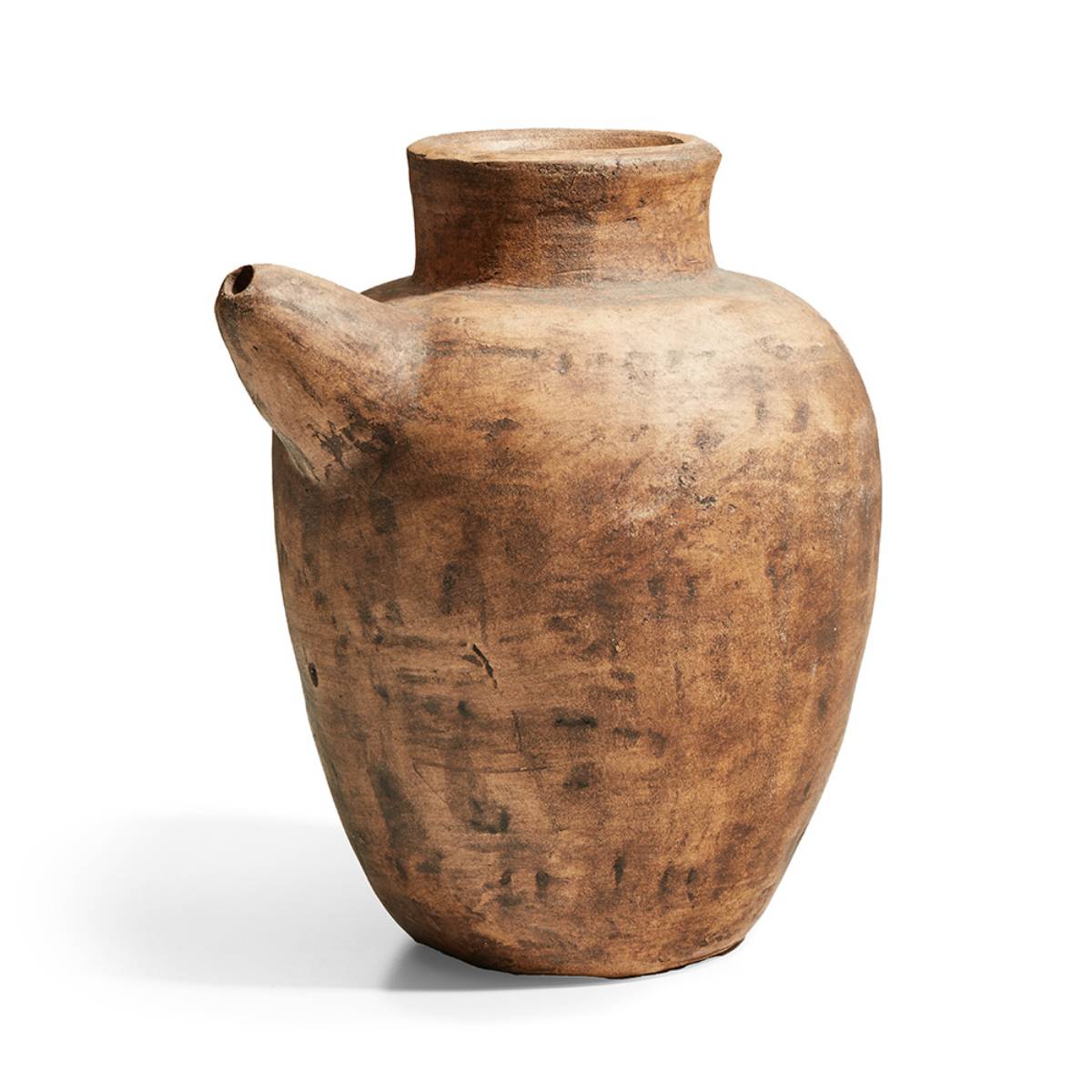 Jarra de cerámica rústica de boca ancha con un pico lateral, de superficie texturizada y tonos terrosos desiguales, sin inscripciones visibles.