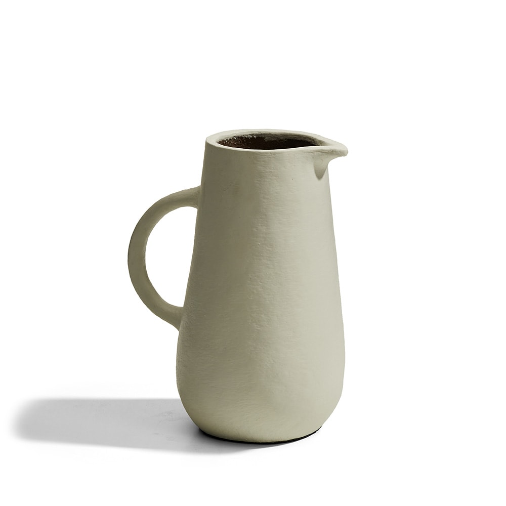 Jarra de cerámica con un acabado mate y textura rugosa, diseño minimalista en color beige con interior oscuro y una sola asa lateral.