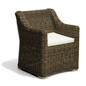 Sillón de mimbre sintético de color marrón oscuro con cojín blanco hueso en el asiento; presenta un diseño robusto con respaldo inclinado y apoyabrazos integrados.