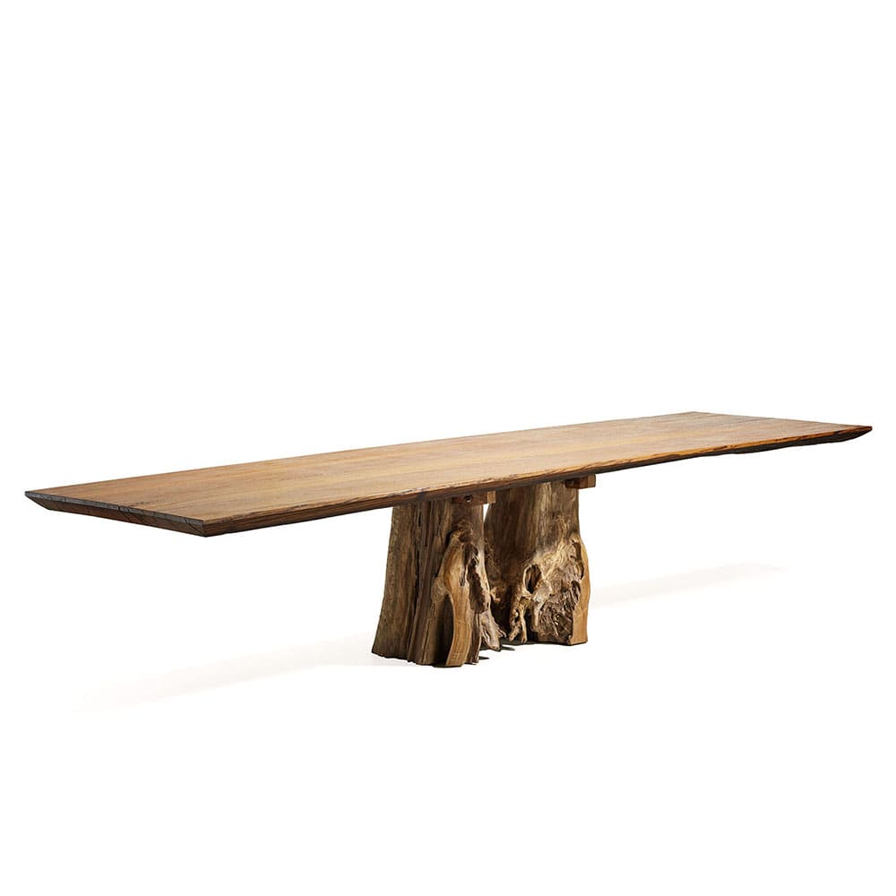 Mesa larga de madera con una tapa lisa y delgada de borde irregular, sostenida por una base hecha de troncos naturales tallados. Presenta un diseño rústico y artístico, resaltando la belleza natural de la madera.