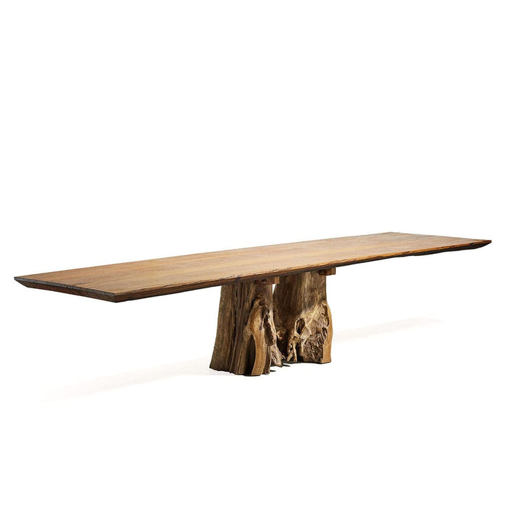 Mesa larga de madera con una tapa lisa y delgada de borde irregular, sostenida por una base hecha de troncos naturales tallados. Presenta un diseño rústico y artístico, resaltando la belleza natural de la madera.