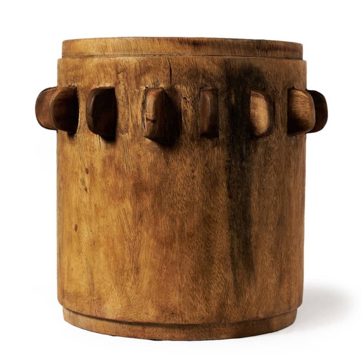Tambor de madera cilíndrico con tonos naturales y una serie de tacos verticales salientes en la parte superior que sirven para ajustar la tensión del parche. No contiene texto visible ni detalles gráficos adicionales.