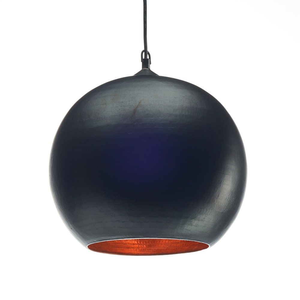 Lámpara colgante de forma esférica con acabado exterior en azul oscuro metálico y el interior en color cobre brillante; cuelga de un cable negro delgado.